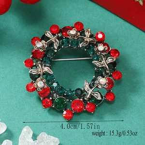 Macro view of Christmas wreath brooch with red and green rhinestones on metal leaves