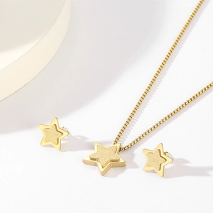 Detail of gold star pendant necklace and matching stud earrings on white background