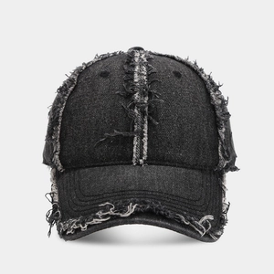 Detail of distressed frayed edges and stitching on a black denim vintage baseball cap