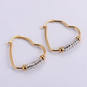 Detail of golden heart-shaped earrings with sparkling rhinestone cylinder accents