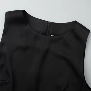 Detail shot of round neckline and back invisible zipper on a black sleeveless dress