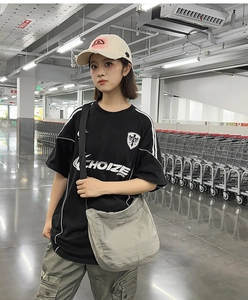 Close-up of black oversized t-shirt featuring white logo print and eagle shield graphic