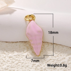 Macro view of a 18mm pink enamel seashell charm with gold plating on sandy background