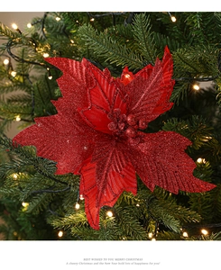 Macro shot of a red glitter poinsettia flower nested in Christmas tree branches with warm lights