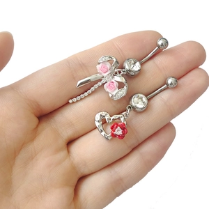 Gros plan de piercings de nombril rose et rouge avec strass et pendentifs en cœur