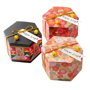 Hexagonal wedding candy boxes with gold floral patterns in black, red, and pink colors