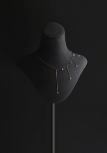 Detail shot of golden tassel necklace with crystal beads on a velvet neck model