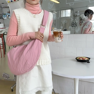 Pink crescent crossbody bag detail featuring lightweight pleated nylon fabric on a model