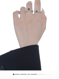 Detailed view of silver rings with black gemstones on model wearing a black suit