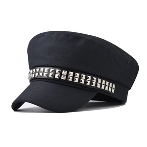 Close-up of black canvas beret with silver rivet studs on a faux leather strap