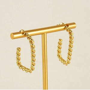 Détail de créoles torsadées dorées présentées sur un support à bijoux professionnel