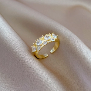 Adjustable gold plated ring with cubic zirconia squares on champagne silk background