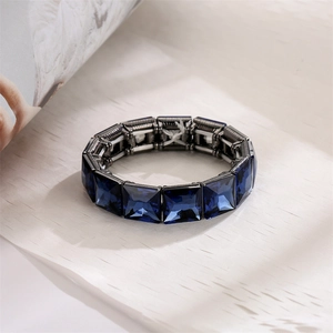 Close-up of faceted dark blue crystals on gunmetal alloy stretch bracelet over wood