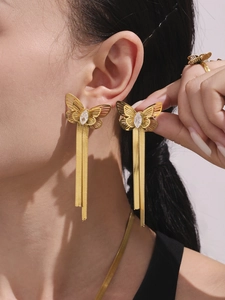 Close-up of gold butterfly drop earrings with zircon inlay and elegant tassel chains