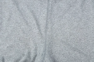 Close-up of light gray knitted fabric texture and fine stitching detail on the garment