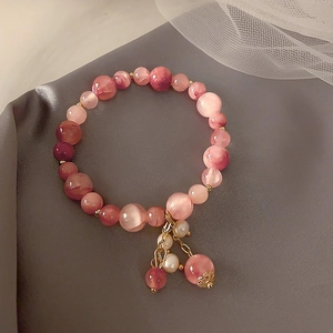 Detailed macro view of a pink strawberry crystal bracelet with gold accents on velvet