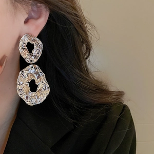 Macro detail of textured silver drop earrings featuring unique crumpled metal finish