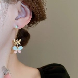 Detail of elegant butterfly resin earrings with zircon studs worn by a model