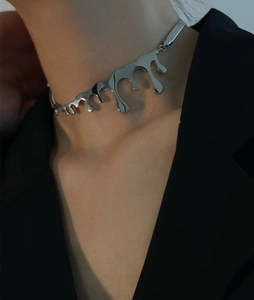 Close-up of silver fluid lava pendant with flat snake chain on a dark garment background