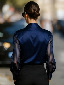Detail of navy blue satin shirt with striped semi-transparent sleeves and loose silhouette