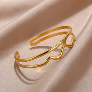 Detail of gold-plated heart bracelet with double-layered wavy lines on silk fabric
