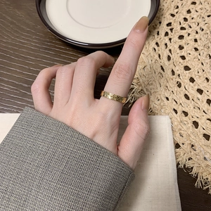 Detail of gold titanium ring with dragon scale pattern on model finger in cozy setting