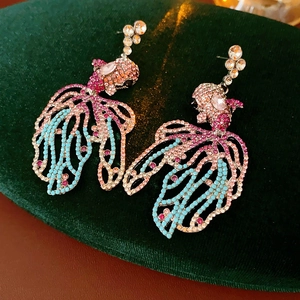 Vue détaillée des boucles d'oreilles poisson vintage avec strass colorés sur velours