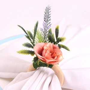 Close-up of wood napkin ring with a peach rose and artificial greenery on white fabric