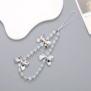 Crystal cube beaded phone strap with elegant silver bow accents on a minimalist grey surface