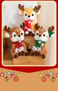 Three plush Christmas reindeer toys with sequined hats and scarves on wooden drawer