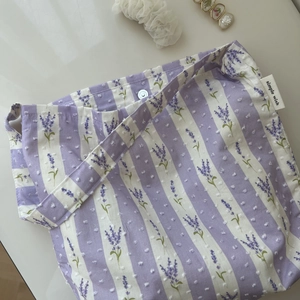 Detail of lavender floral print and textured cotton fabric on a striped shoulder bag