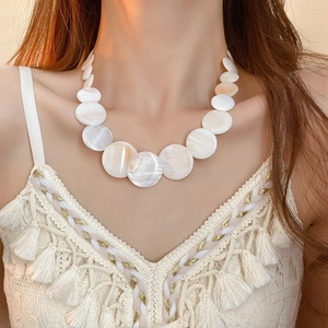 Detail of natural shell necklace with white iridescent discs worn by a model