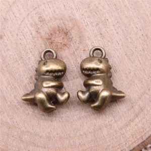 Pair of antique bronze dinosaur pendants for DIY jewelry making on wooden background