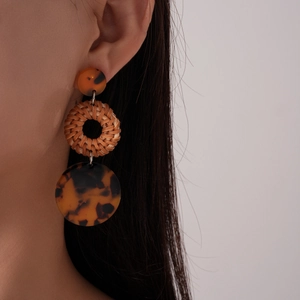 Detail of vintage geometric earrings with amber resin and handmade woven rattan circles