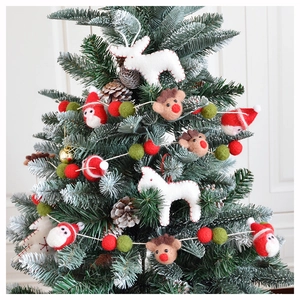 Detail von Rentier- und Weihnachtsmann-Filzanhängern an einem grünen Weihnachtsbaum