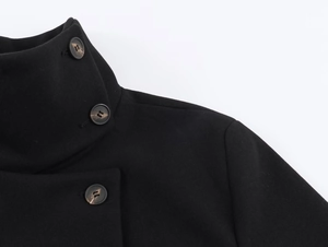 Detailed macro view of the stand collar and marbled buttons on a black wool coat