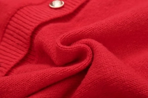 Detail der roten Strickjacke mit gerippter Textur und Metallknöpfen mit Randverzierung