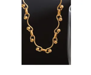 Detailed close-up of golden wavy bar chain necklace with polished sphere accents