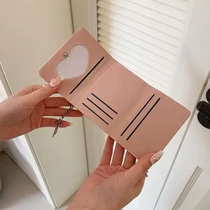Pink trifold wallet with bow and heart photo slot shown open against white background