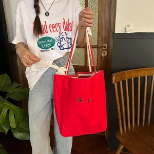 Detailed embroidery of a butterfly on a large red striped canvas tote bag