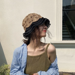 Detail of hand-woven straw bucket hat with black lace trim and ruffled edges for summer