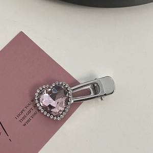 Macro detail of silver alloy heart-shaped hair clip with pink gems and crystals