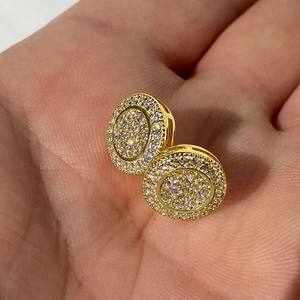 Close-up of hand holding gold round pave cubic zirconia stud earrings showing scale