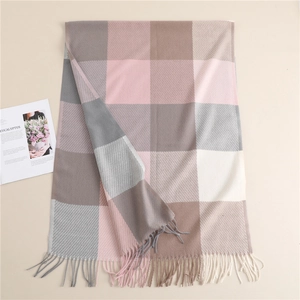 Detail of soft plaid scarf featuring tassels in pink, grey, and beige color block design