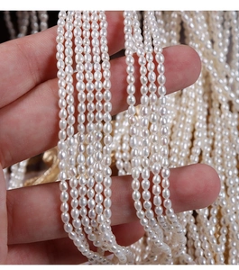 Macro detail of high-luster 2.5mm natural freshwater seed pearls held in hand for DIY jewelry