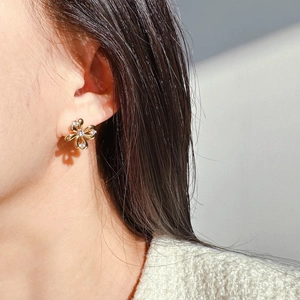 Exquisite gold floral stud earrings with zircon petals on female model in sunlight