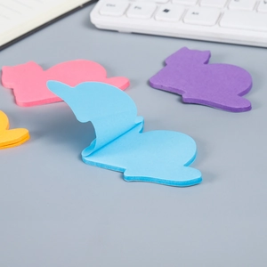 Cute cat-shaped colorful sticky notes set on office desk with laptop and keyboard