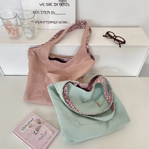 Detail of pink and mint green suede tote bags with leopard print lining on white steps