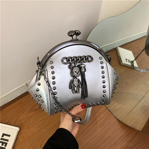Silver rivet shell bag with chain strap and bear pendant, shown held in hand