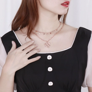 Détail d'un collier double couche en or rose avec pendentifs étoile, zircon et cœur